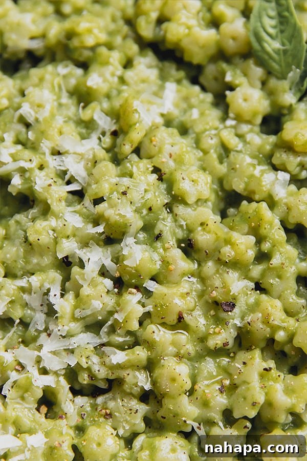 A close-up view of a bowl of basil pesto stelline, showing the tiny star-shaped pasta coated in green pesto, with hints of cheese and fresh basil, ready for a delightful meal.