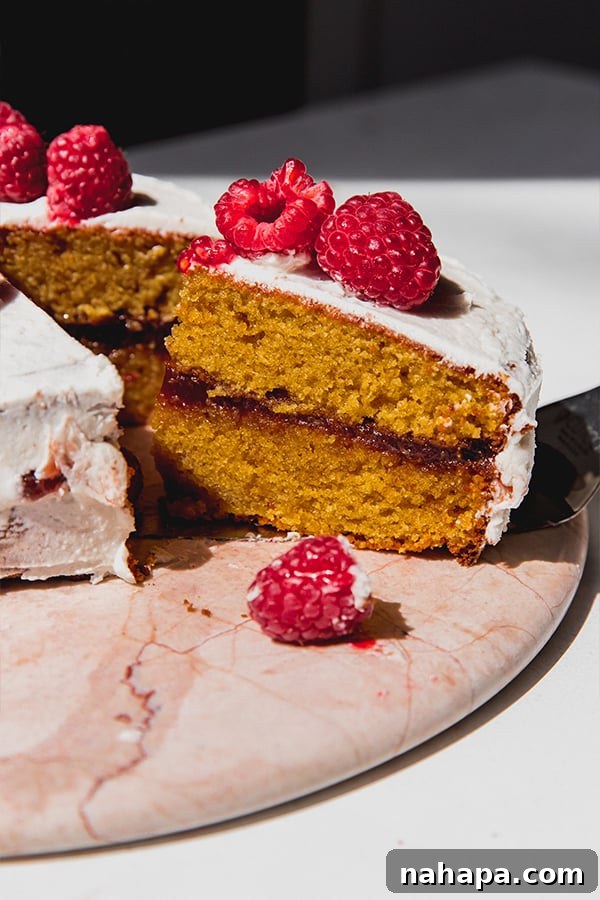 A beautifully sliced gluten-free white chocolate raspberry cake, showcasing its moist layers and luscious raspberry filling.