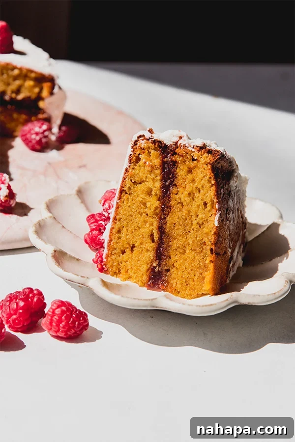 A perfectly portioned slice of gluten-free white chocolate raspberry cake, ready to be enjoyed on a plate.