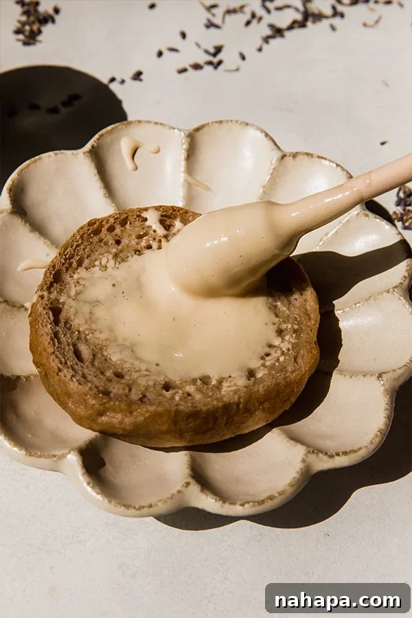 A knife spreading homemade lavender whipped honey on a piece of bread, showcasing its rich and creamy texture.