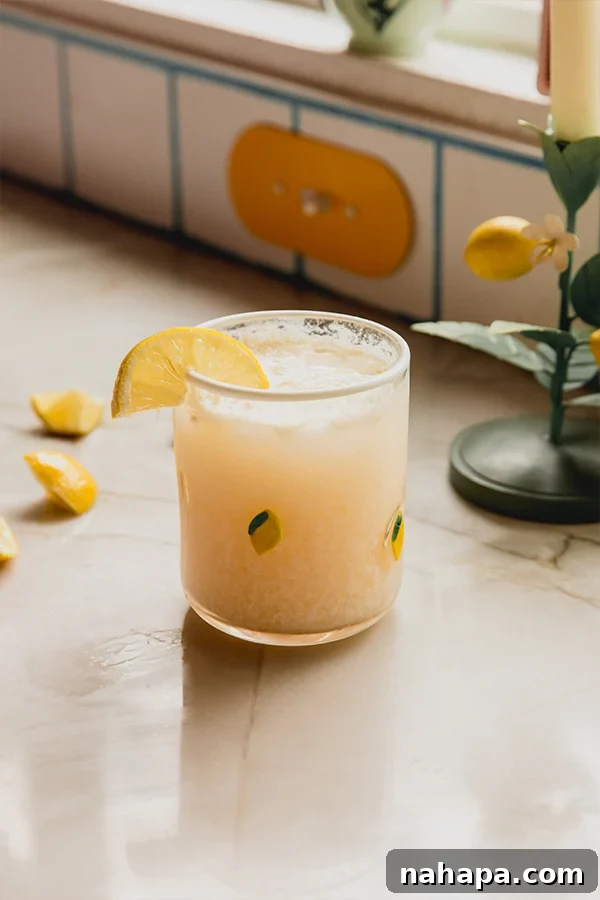 A glass of Italian Lemon Cream Soda sitting on the counter, garnished with a fresh lemon slice.