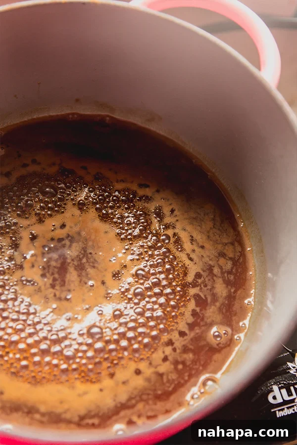 A pot of homemade almond syrup after cooking, cooling on the stovetop.