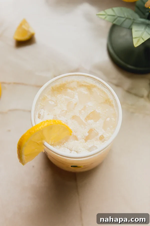 A glass of Italian Lemon Cream Soda sitting on the counter, with a blurred background, highlighting its refreshing appeal.