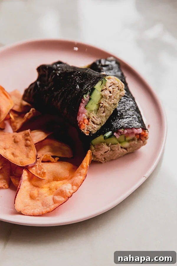 A plate with a tuna seaweed wrap cut in half with chips ready to be enjoyed.