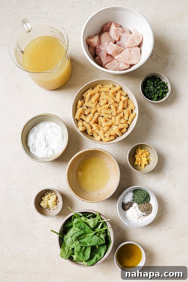 All of the ingredients for lemon chicken pasta bake before cooking are laid out on a white surface.