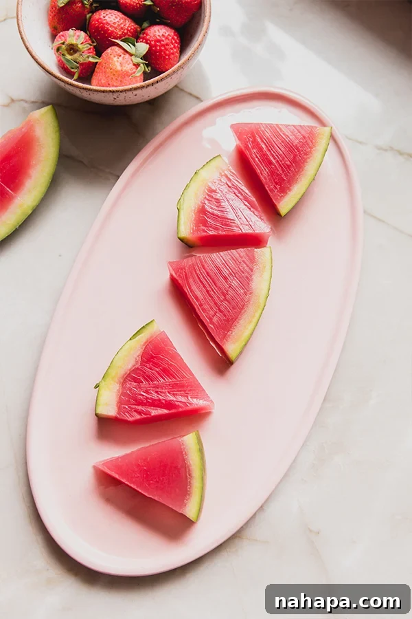 Bright pink watermelon jello slices artfully arranged in a watermelon rind