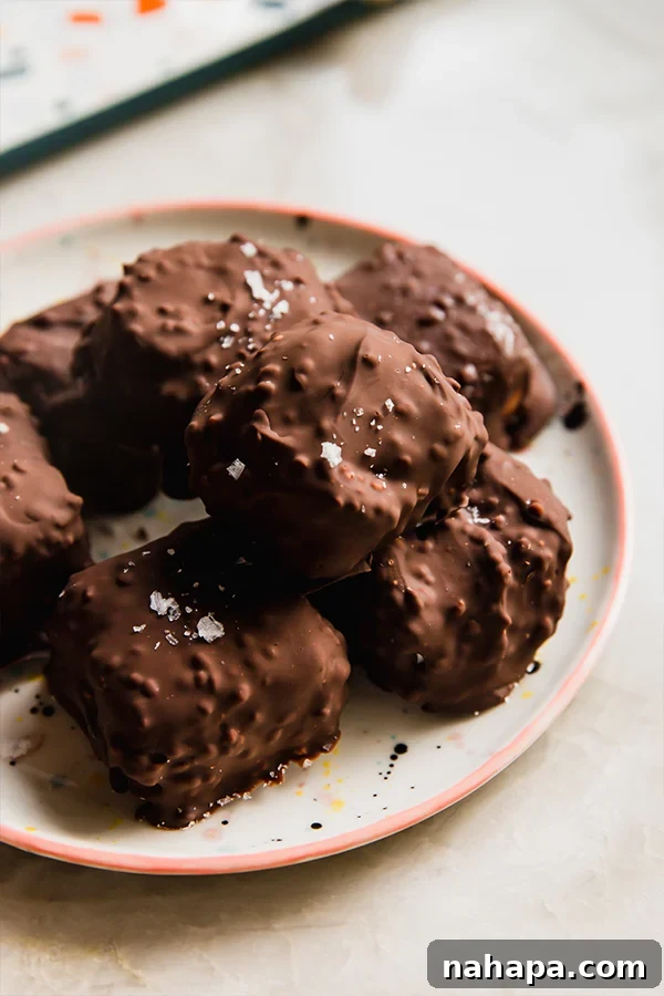 Chocolate-coated dairy-free strawberry crunch ice cream bites being placed on parchment paper
