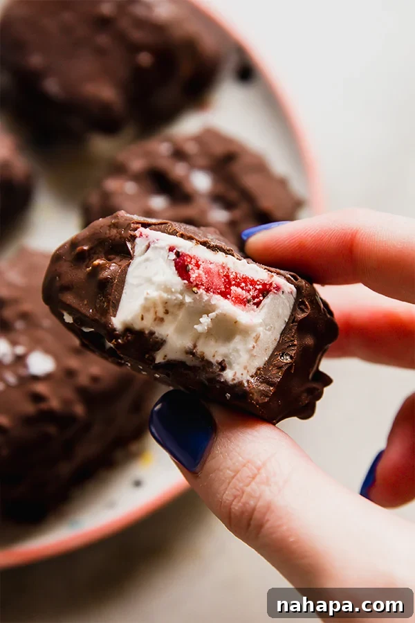 Dairy-Free Strawberry Crunch Ice Cream Bites on a wire rack with a bowl of melted chocolate