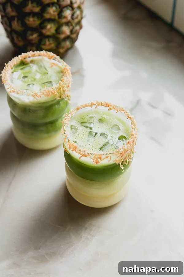 Jade Piña Paradise 5 Matcha Piña Colada garnished with a pineapple wedge and toasted coconut