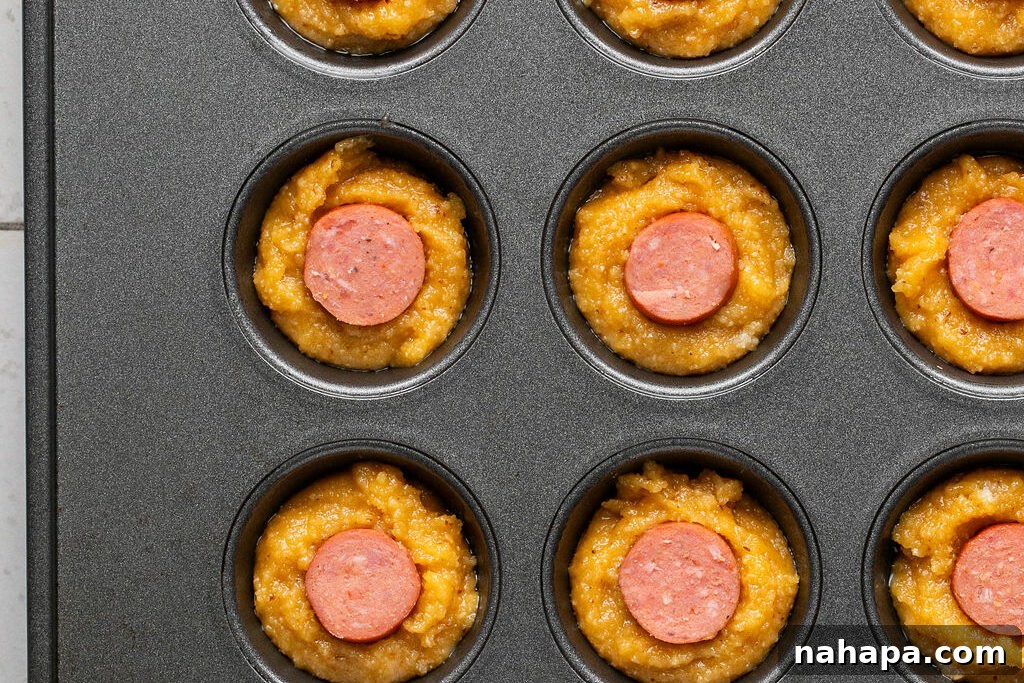 Mini corn dog muffins unbaked in a muffin tin, ready for the oven.