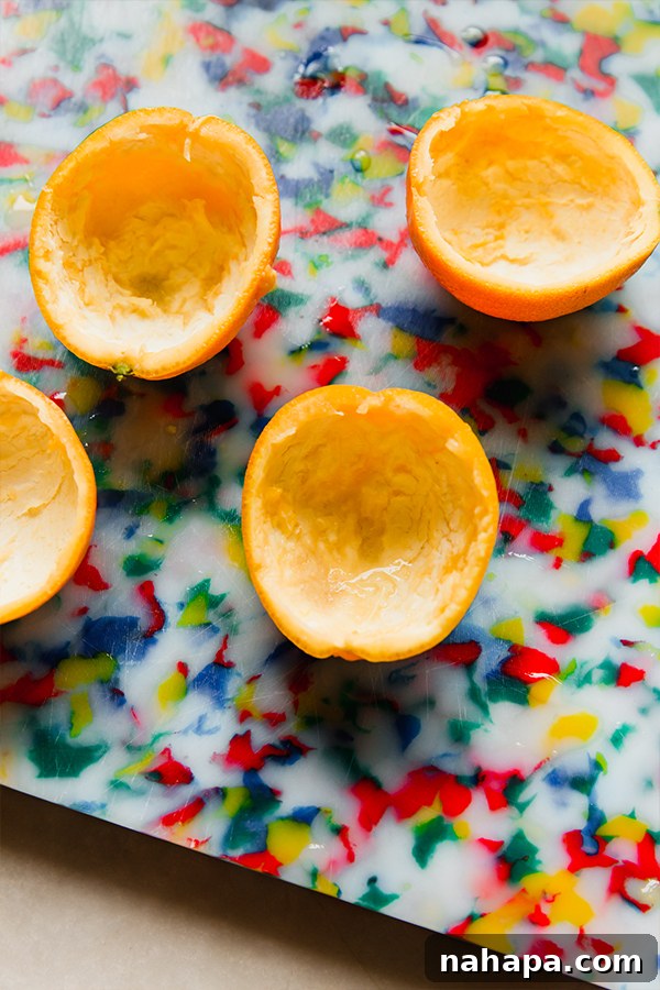 The orange jello mixture being poured into hollowed orange peels, set in ramekins.