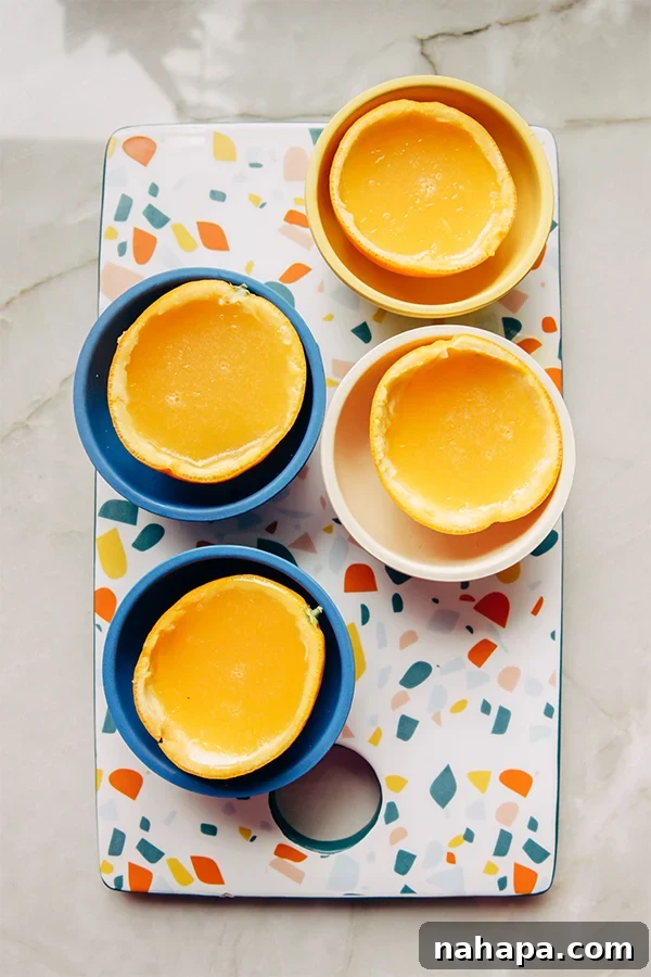 Collection of orange jello slices in their natural peels, arranged artfully on a white surface.