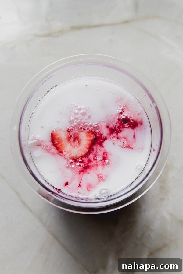 Preparing the Ninja Creami pint with fresh strawberries for the pink drink sorbet base.