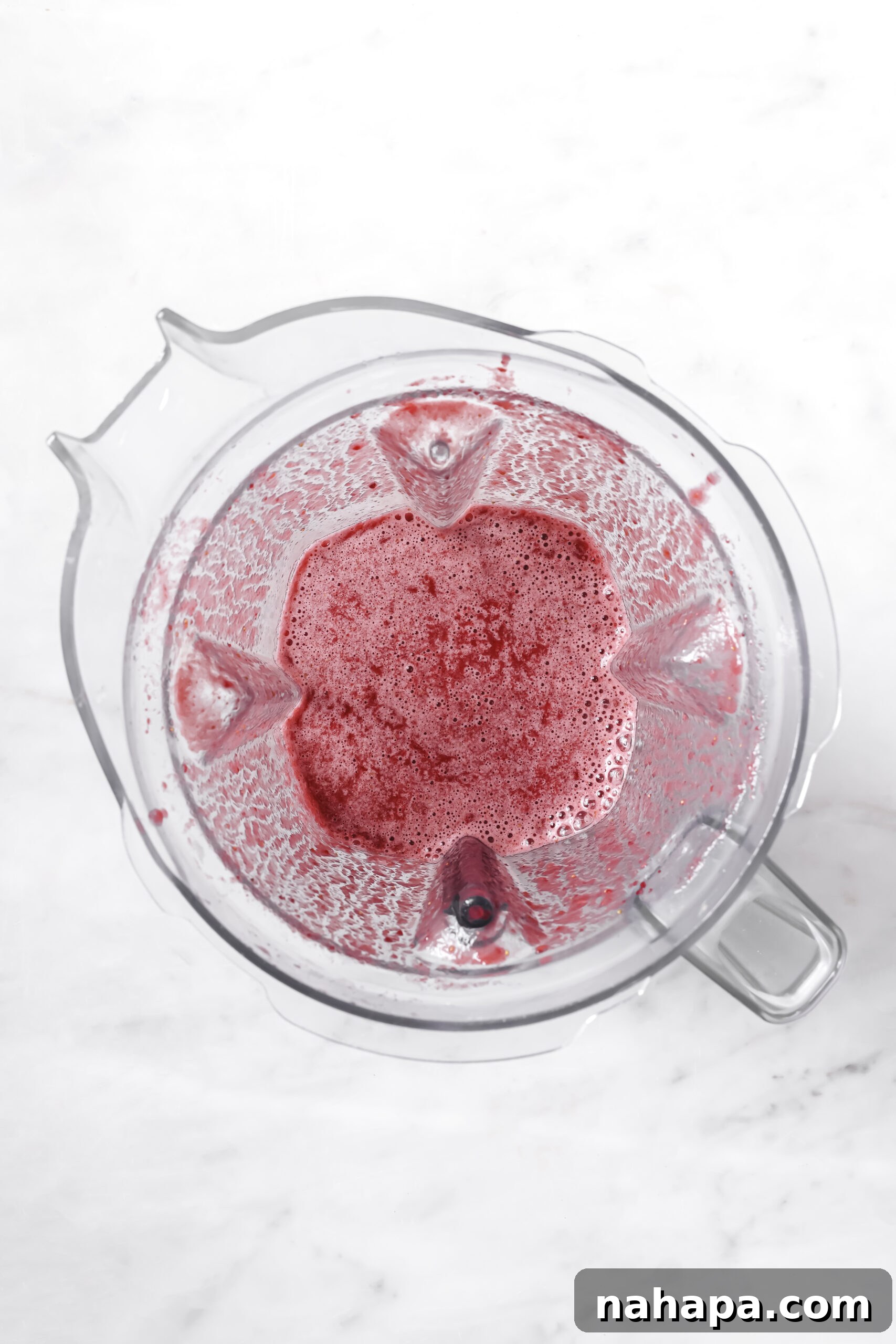 Pouring strawberry-beet mixture into a freezer pop bag using a funnel