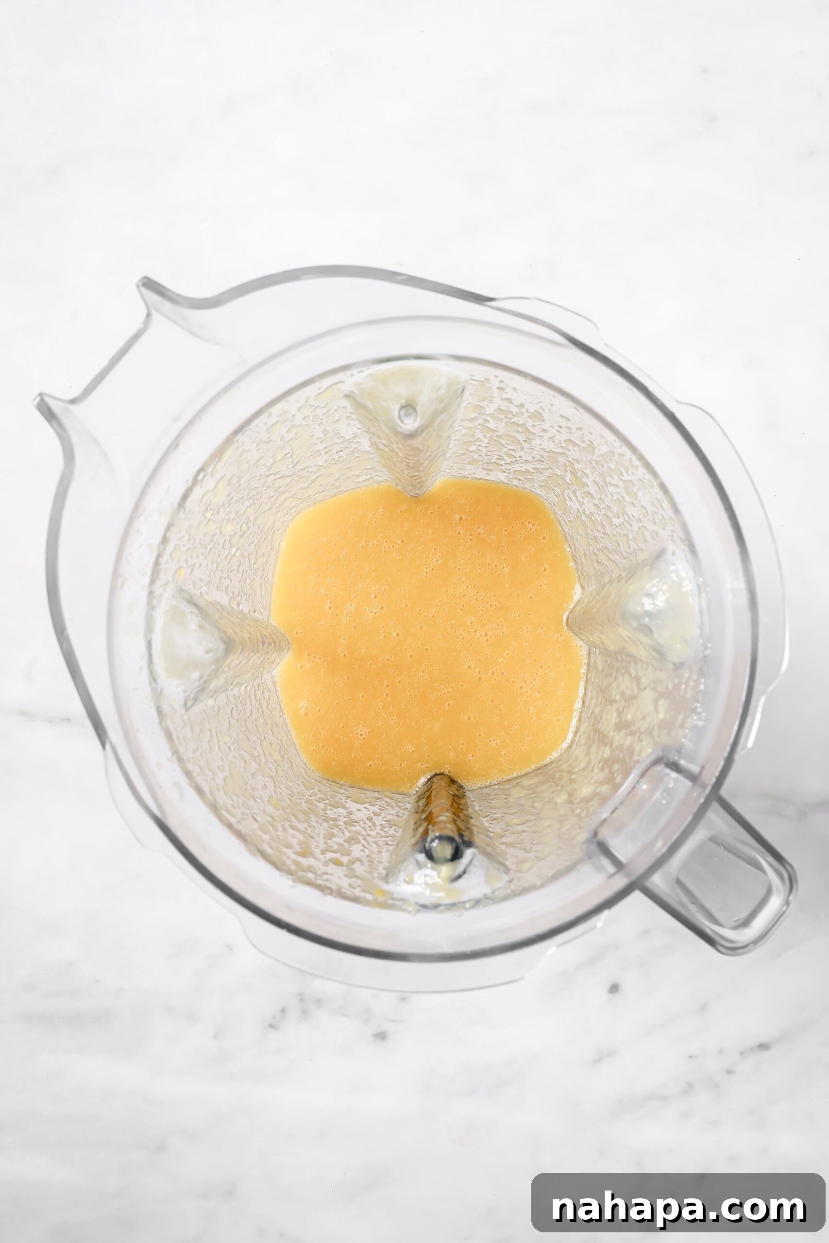 Pouring mango-peach mixture into a freezer pop bag using a funnel