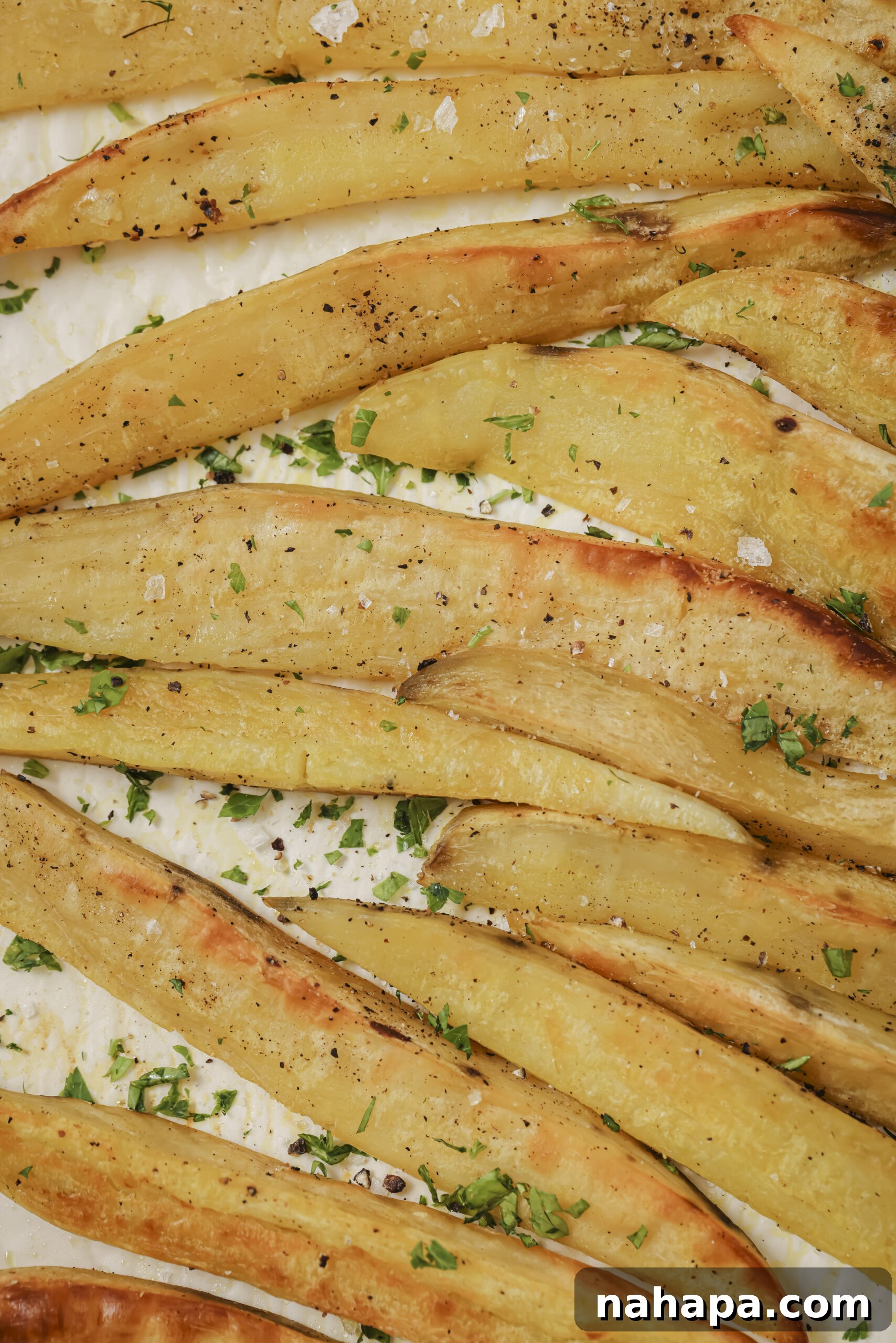 A serving of crispy sweet potato fries, garnished with fresh parsley, ready for dipping and enjoyment.