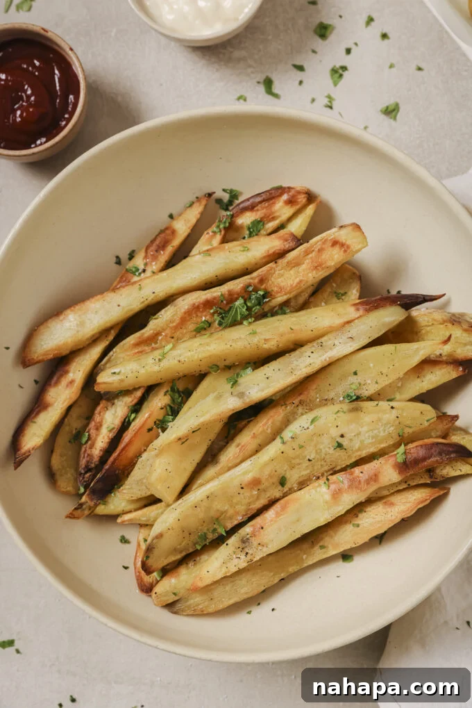 A beautifully presented bowl of crispy baked white sweet potato fries, garnished with fresh parsley, ready to be enjoyed.