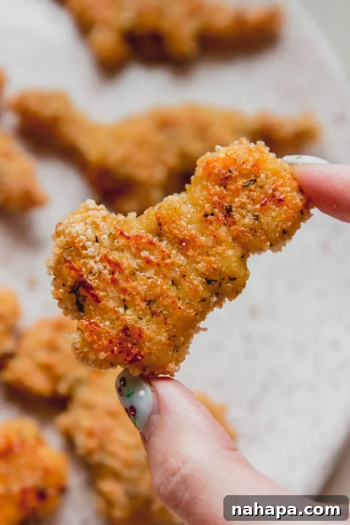 Person holding a gluten-free dino nugget.