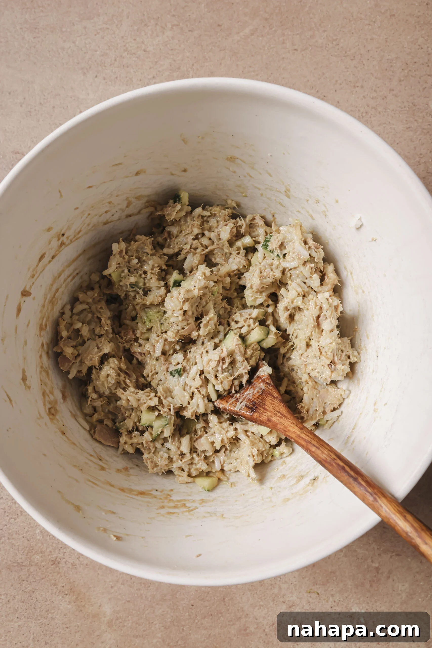 Avocado, tuna, rice and cucumber fully mixed in a white bowl.