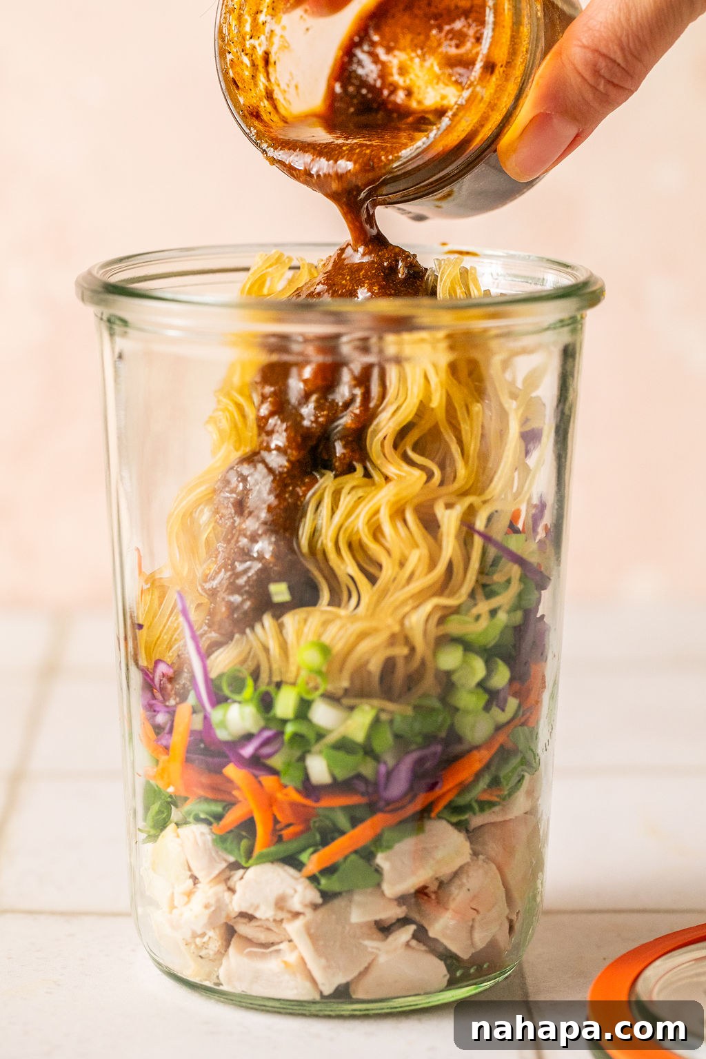 Elevated Gluten-Free Noodle Cups: Healthy Homemade Comfort 7 Cooked chicken, veggies, green onion, a brick of gluten free ramen layered in a glass jar with sauce pouring in.