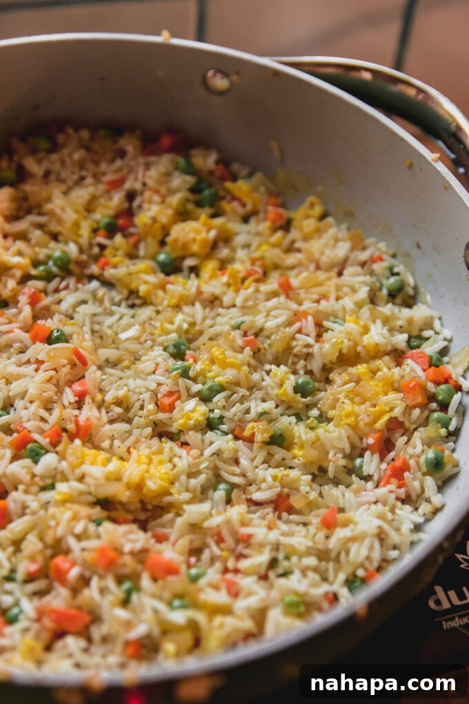 Cooked fried rice with egg, pease and carrots in a pan.