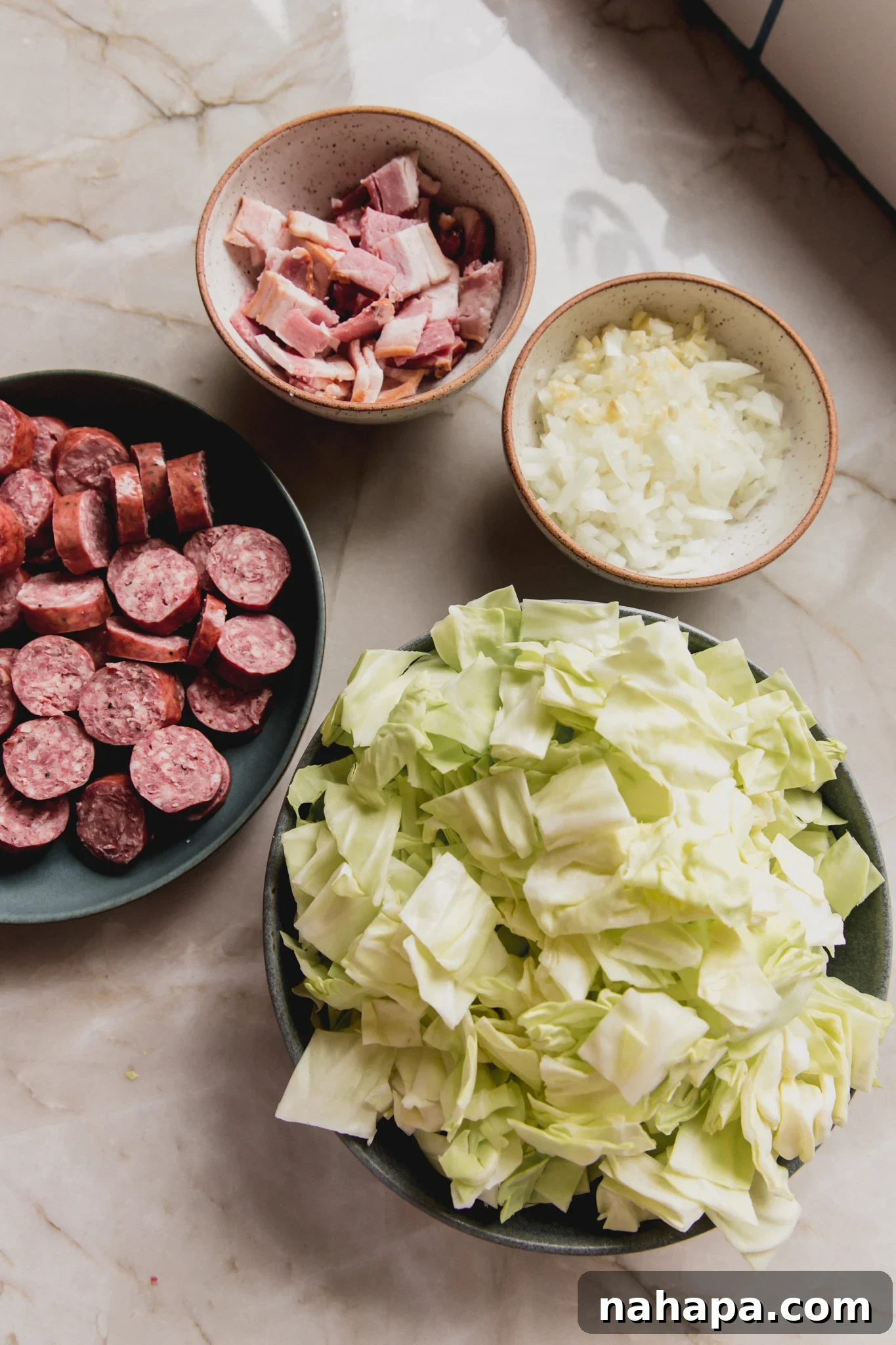 Down-Home Skillet Cabbage and Sausage 3 Various ingredients for Southern fried cabbage arranged in small bowls.
