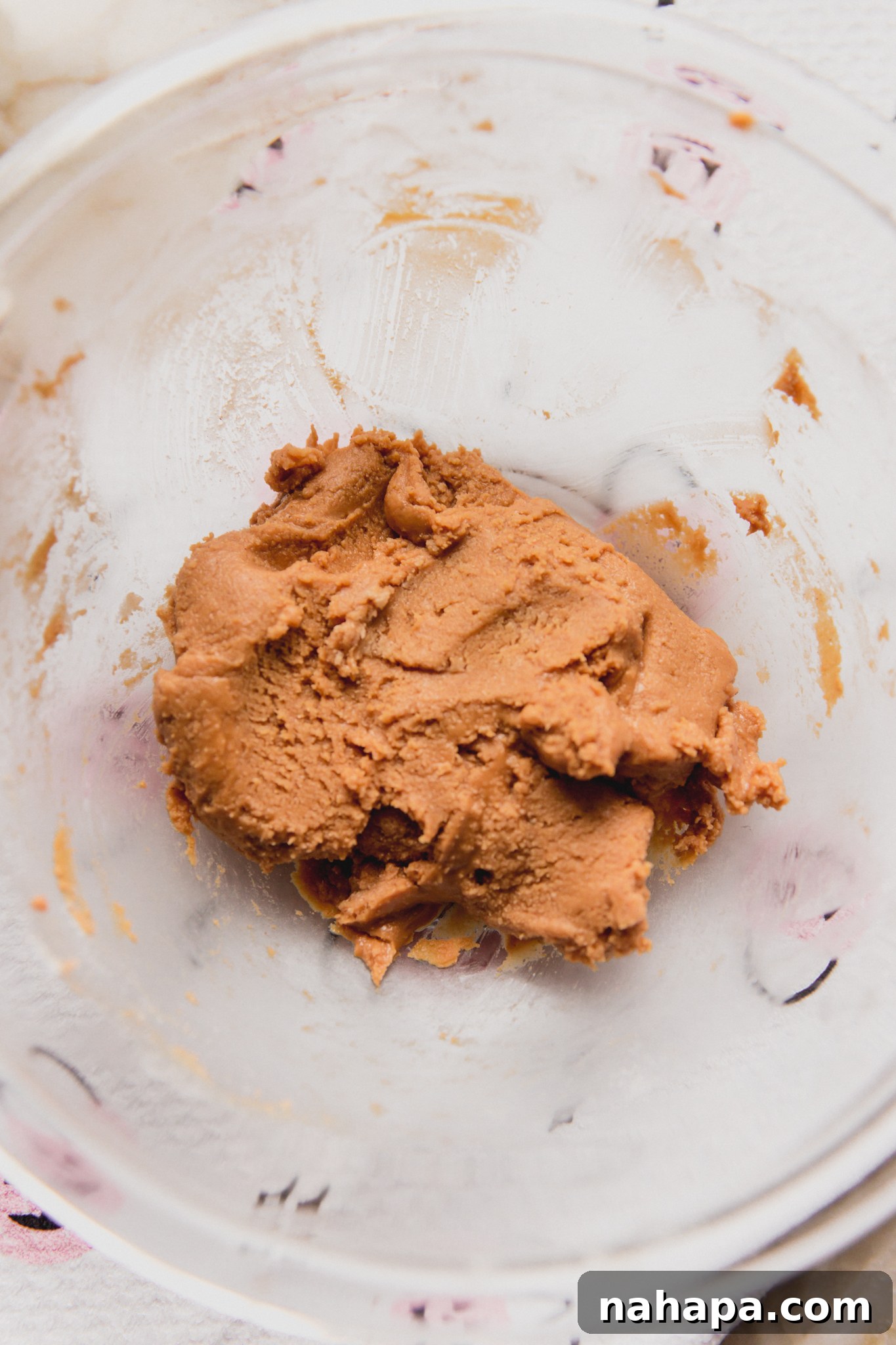 Bowl with almond butter, maple syrup, and coconut flour mixed into a cohesive, dough-like filling.