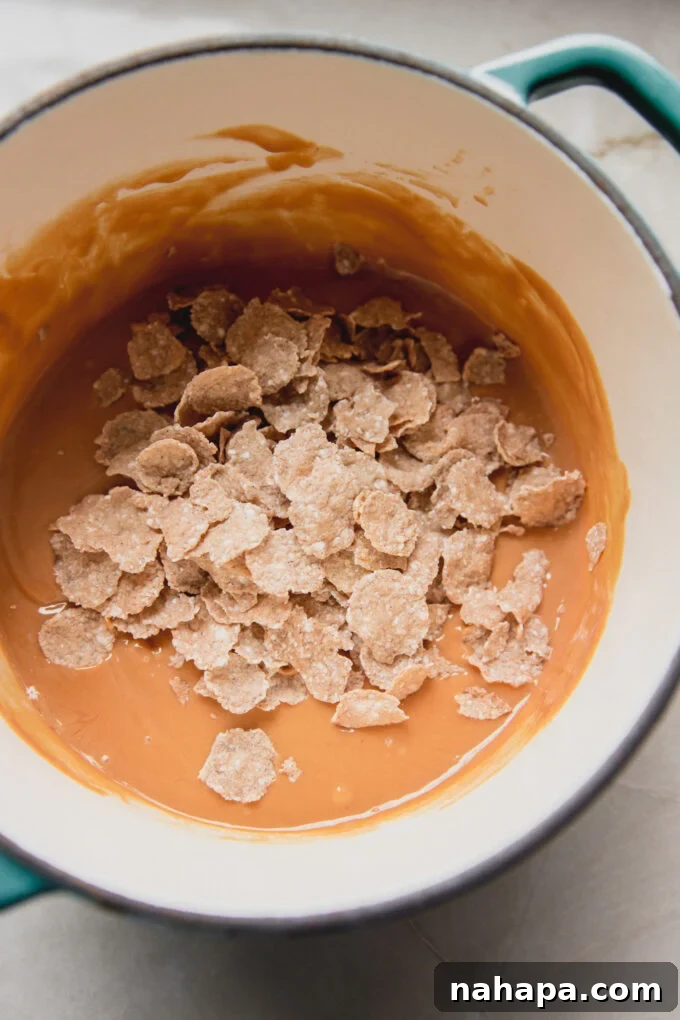 Melted nut butter, honey, and vanilla mixture in a small pot, ready for cereal to be folded in.