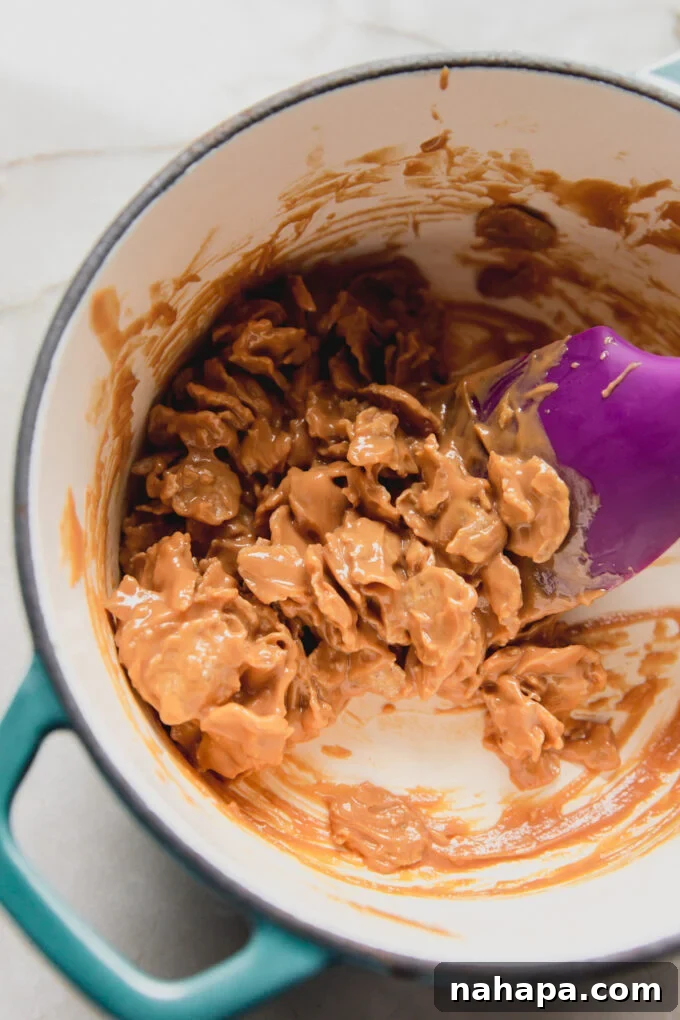 Nut butter and flake cereal mixture, combined and still warm in a pot, showing the crispy texture.
