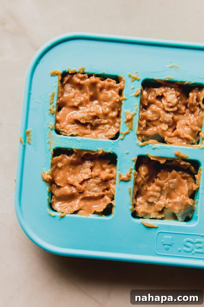 Mini Butterfinger copycat filling squares neatly arranged in a silicone mold, ready for freezing.