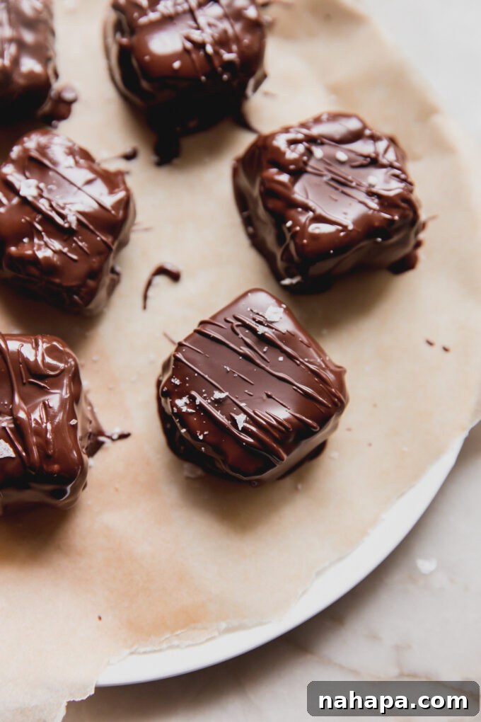 Finished mini Butterfinger copycats on a platter, glistening with chocolate and topped with flakey salt.