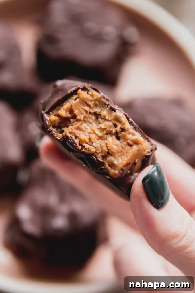 A mini Butterfinger copycat, freshly bitten in half, showing its crispy, golden filling and chocolate coating.