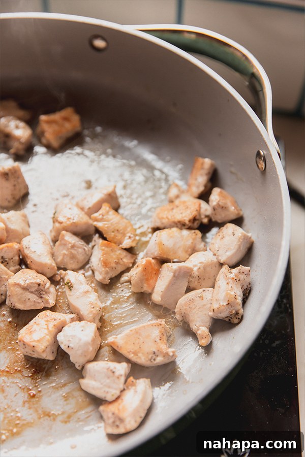 Perfectly cooked, diced chicken pieces, golden brown and juicy, sautéed in a pan and ready to be combined with other stir fry ingredients.