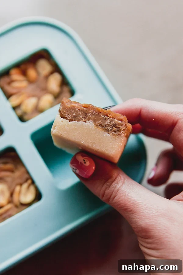 Snickers bars with two layers (nougat and caramel) after being pressed and set in small square silicone molds, before being dipped in chocolate.