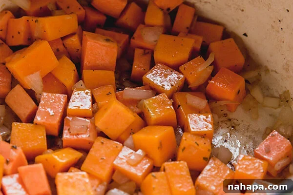 Diced sweet potato and onion gently cooking in a large pot, forming the aromatic base of the chili.