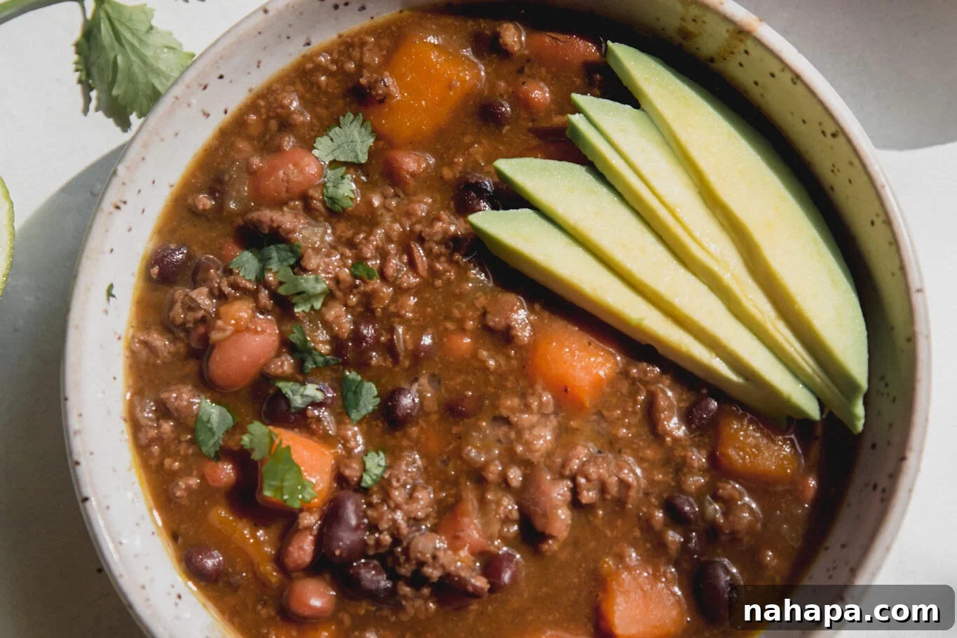 A vibrant bowl of nightshade-free chili, beautifully garnished with fresh avocado slices, ready to be served.