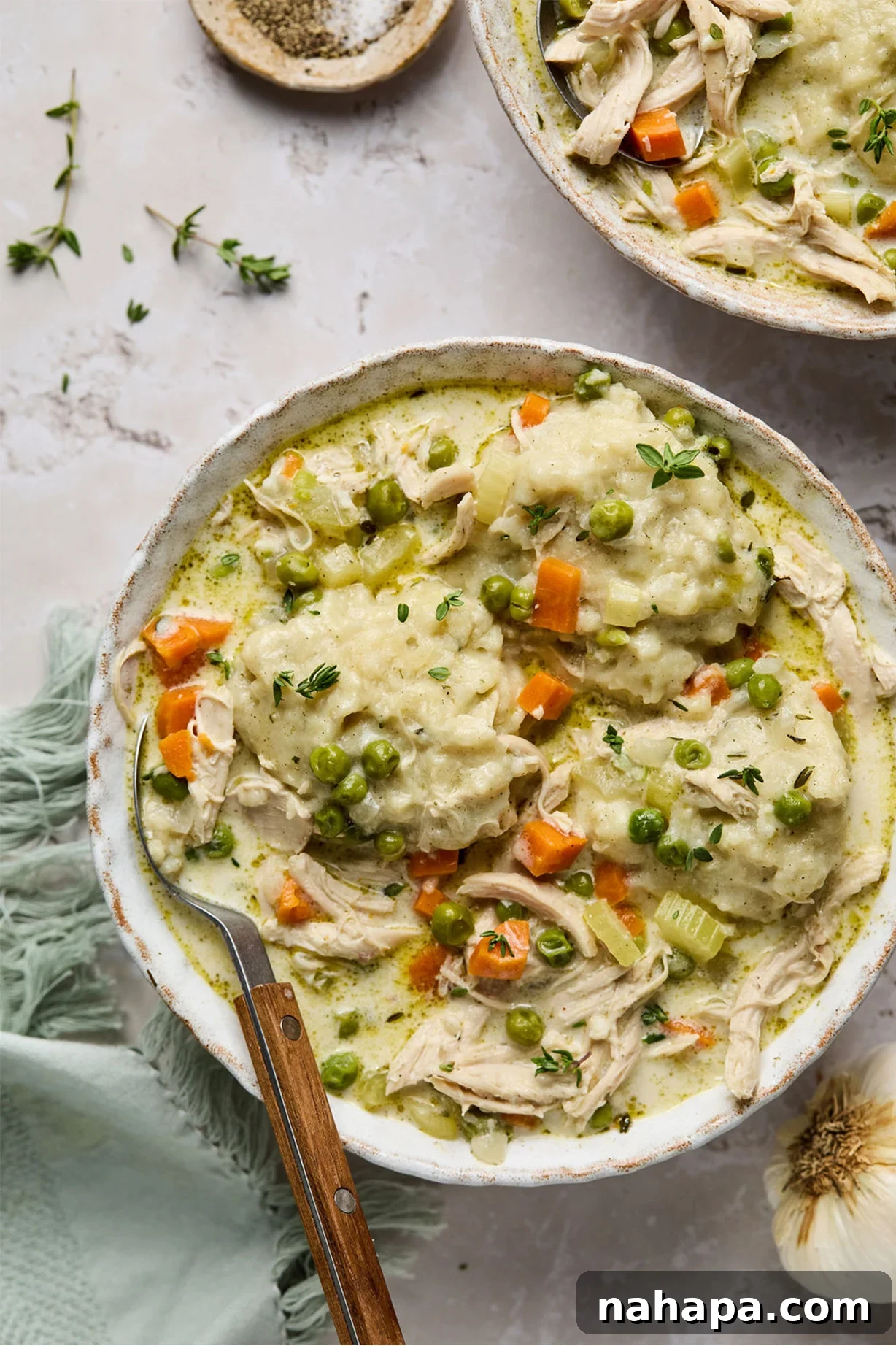 A bowl of creamy gluten-free chicken and dumplings with a spoon, ready to be enjoyed.