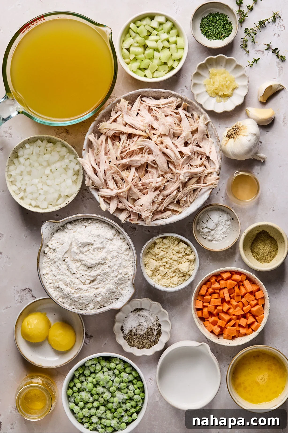 Various gluten-free chicken and dumpling ingredients laid out in separate bowls on a wooden table.