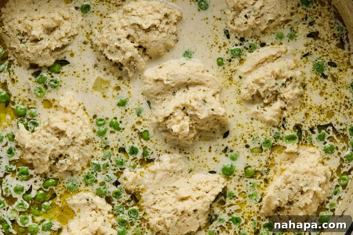 Gluten-free dumpling dough scooped onto the simmering chicken and vegetable soup.