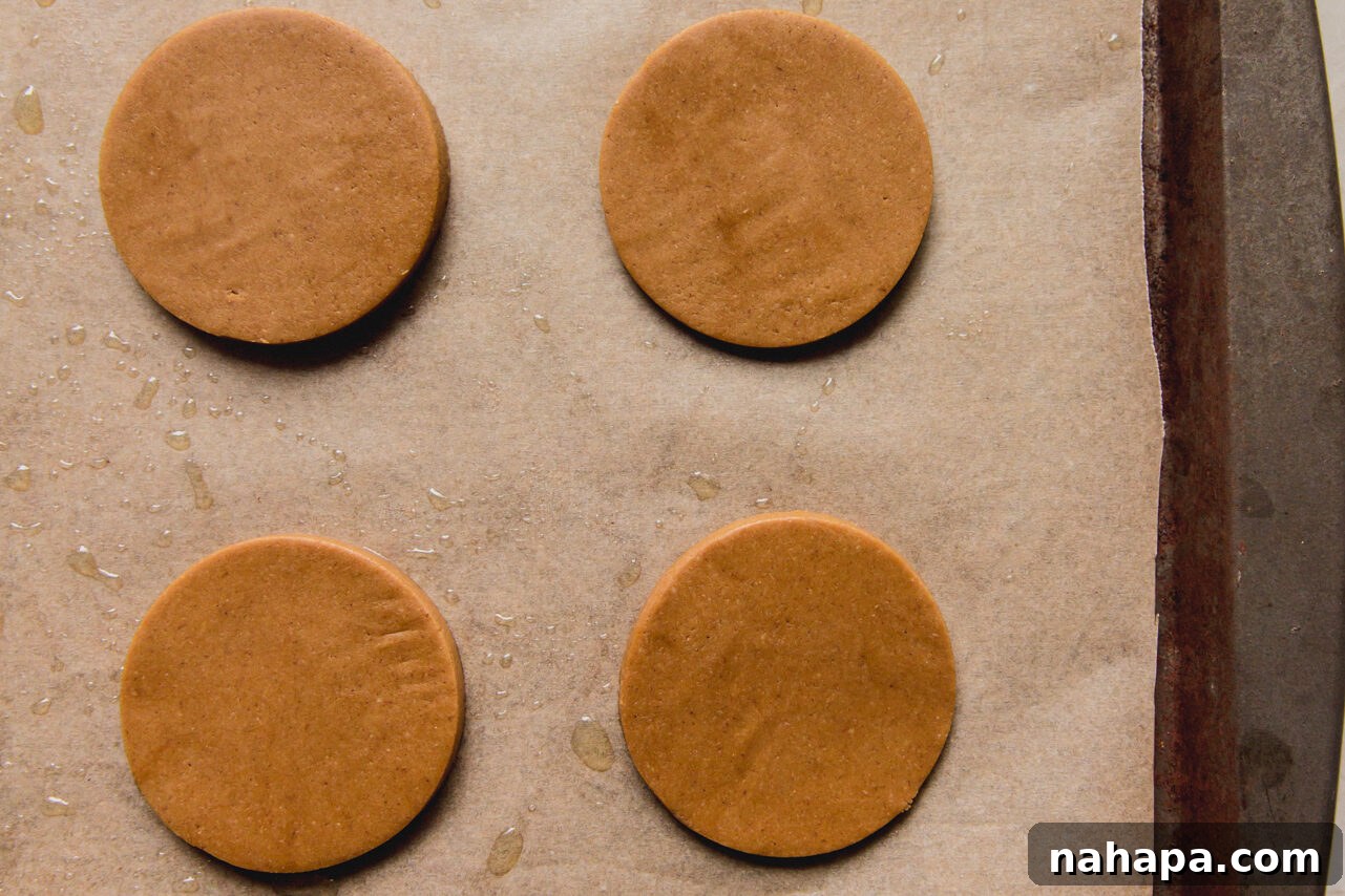 A baking sheet neatly arranged with nine unbaked gingerbread cookies, perfectly spaced for even cooking.