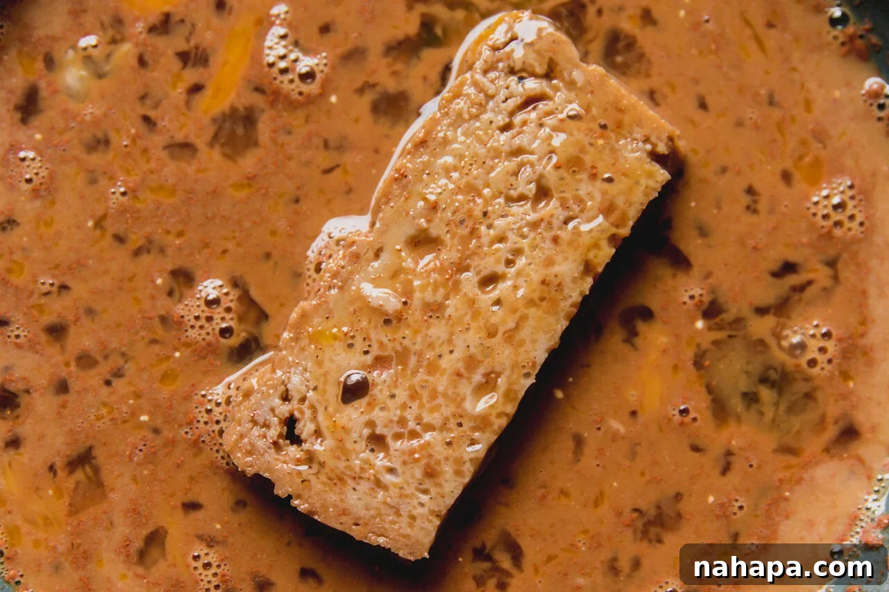 gluten free bread dipped in a bowl of french toast batter.