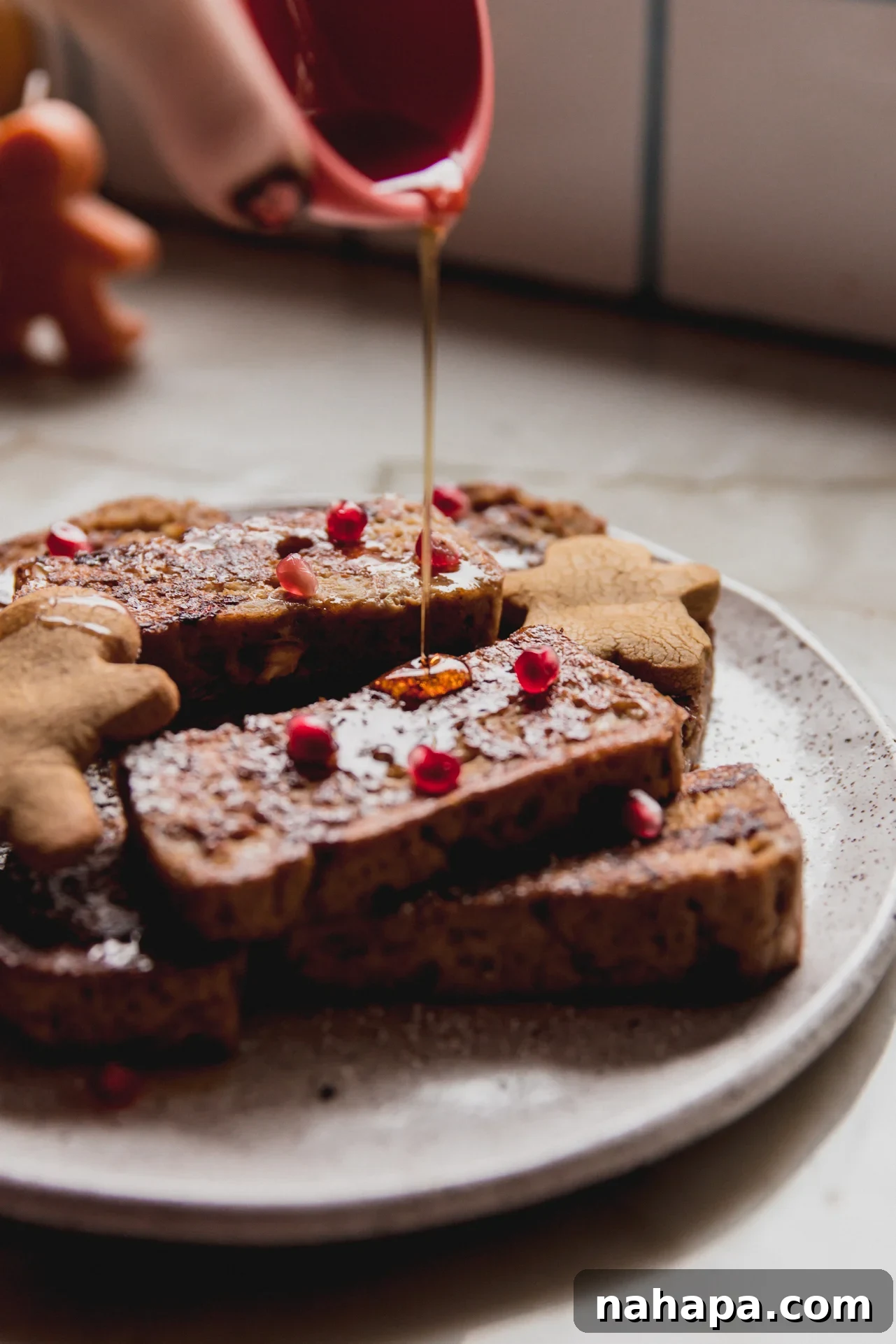 Gingerbread french toast on a plate with maple syrup being poured over.