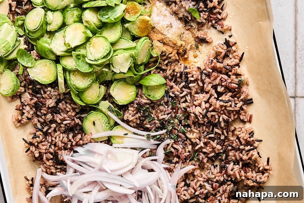 Cooked white rice, shredded brussels, shallots, and spices on a baking sheet.