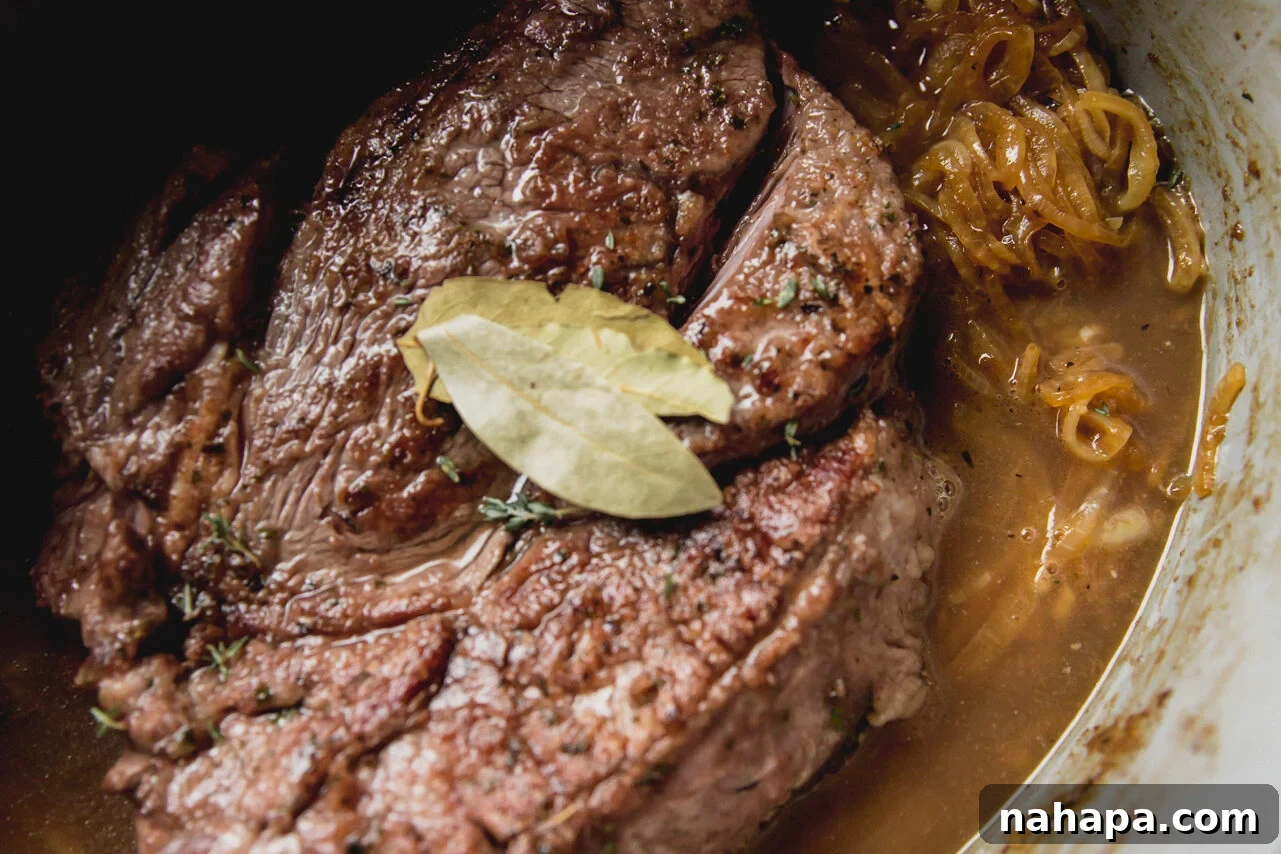 French Onion Braised Beef 9 The assembled pot roast in the Dutch oven, with the seared beef nestled among the softened onions, covered in broth, and ready to be placed in the oven.