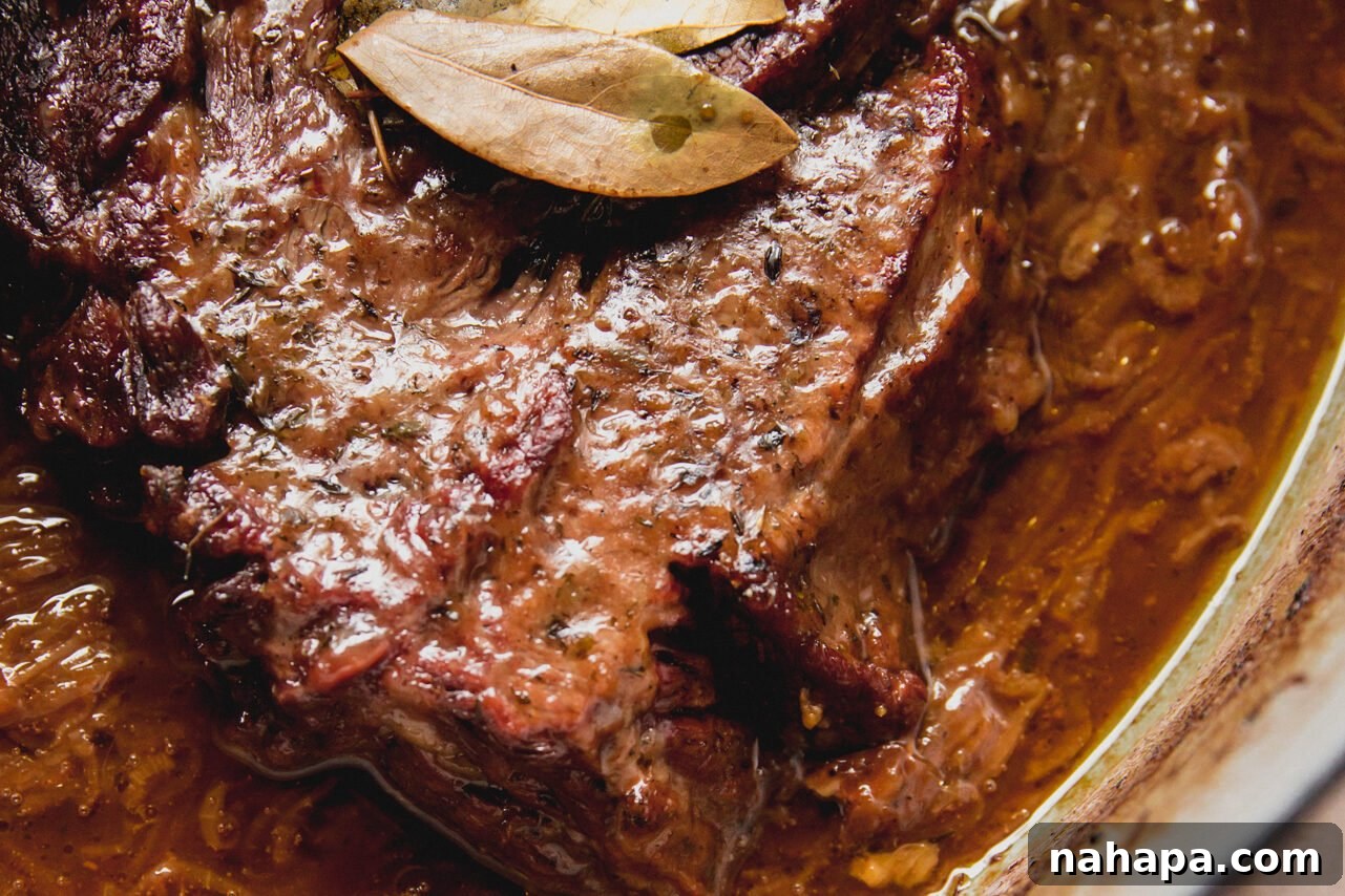 French Onion Braised Beef 10 The fully cooked French onion pot roast, tender and succulent, resting in its rich, savory broth inside the Dutch oven, ready to be shredded.