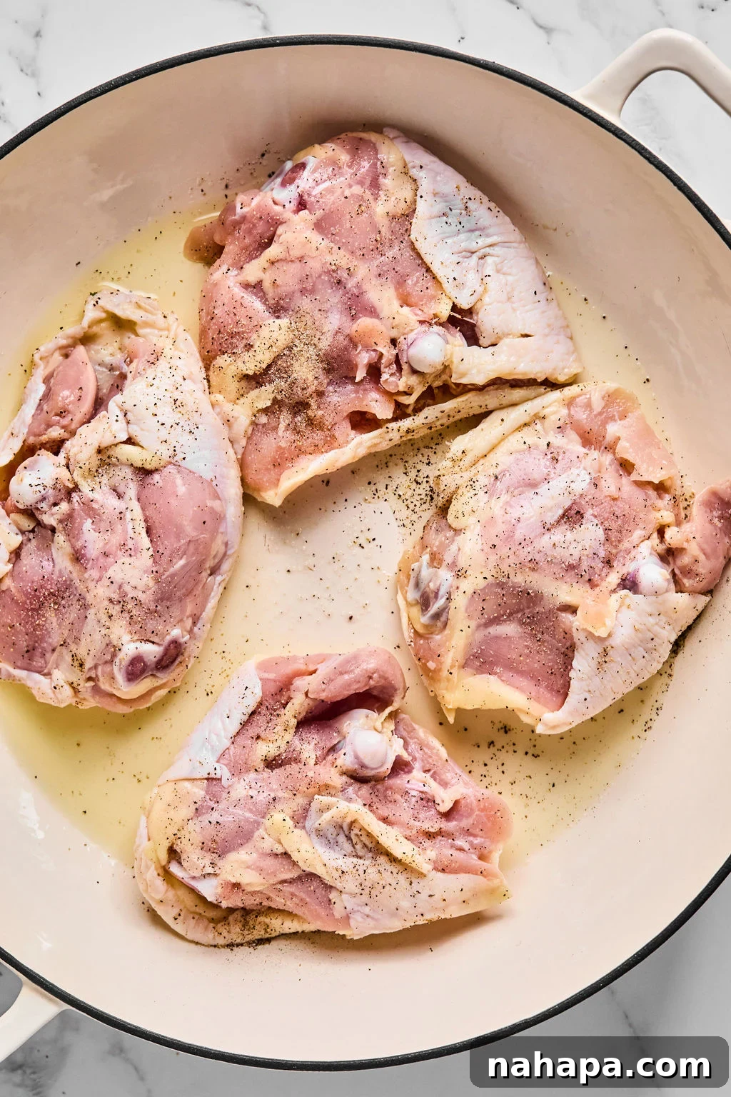 Chicken thighs placed skin side down in a hot skillet, ready for searing.