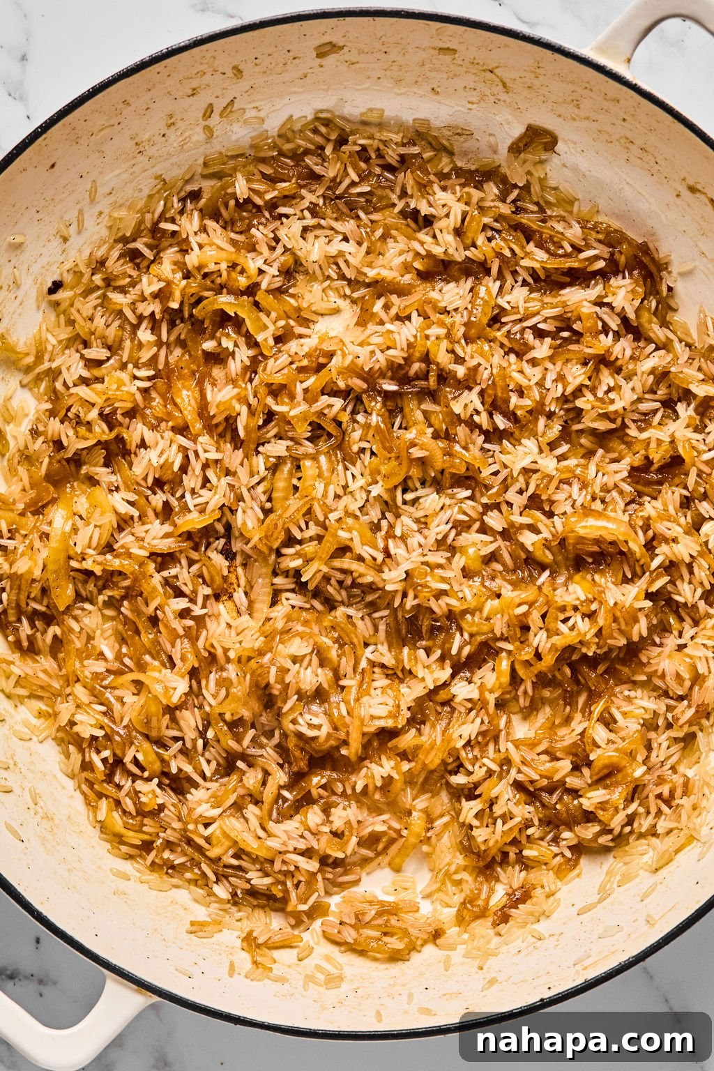 The pan with caramelized onions and toasted jasmine rice, ready for the liquids and chicken to be added.