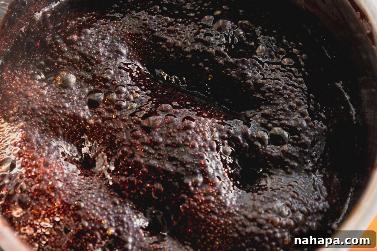 The elderberry and honey mixture simmering to the hard crack stage in a pot, a candy thermometer clipped to the side.