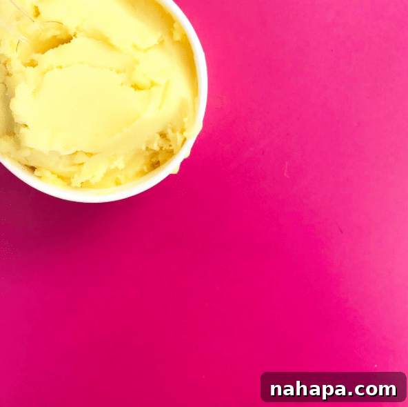 A cup of mashed potatoes on a pink background.