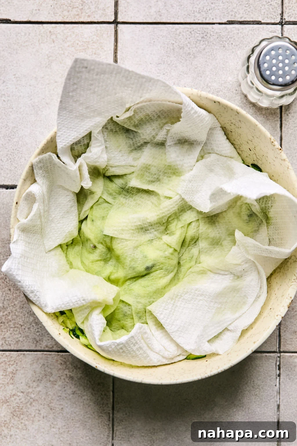 Zesty Gluten-Free Turkey Feta Bites 4 Freshly shredded zucchini in a bowl with a paper towel on top, ready for excess water to be squeezed out.